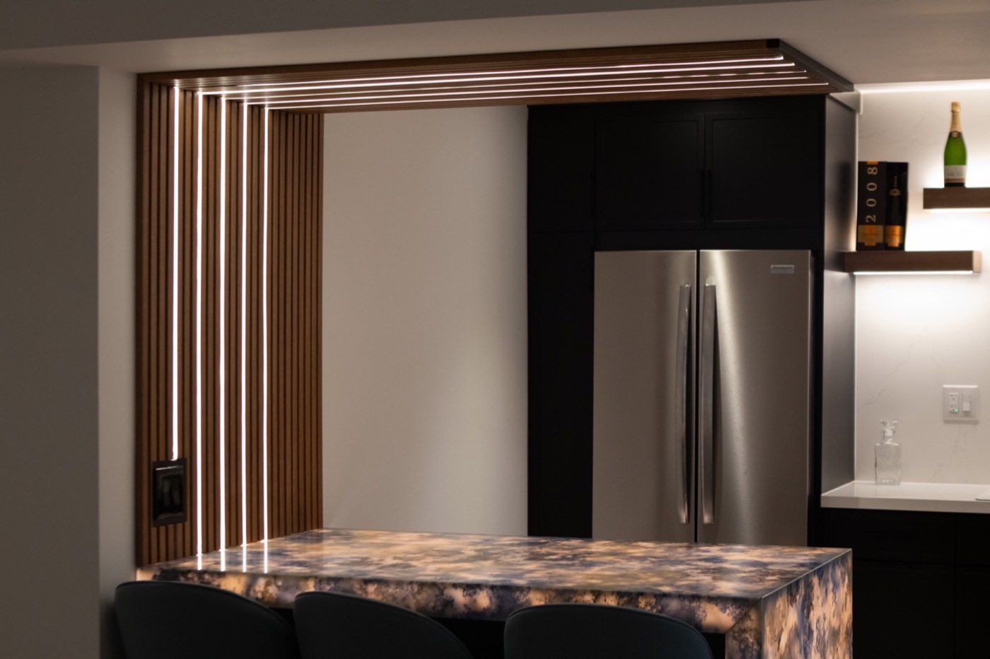 Kitchen bar with stone island under a lit slat canopy