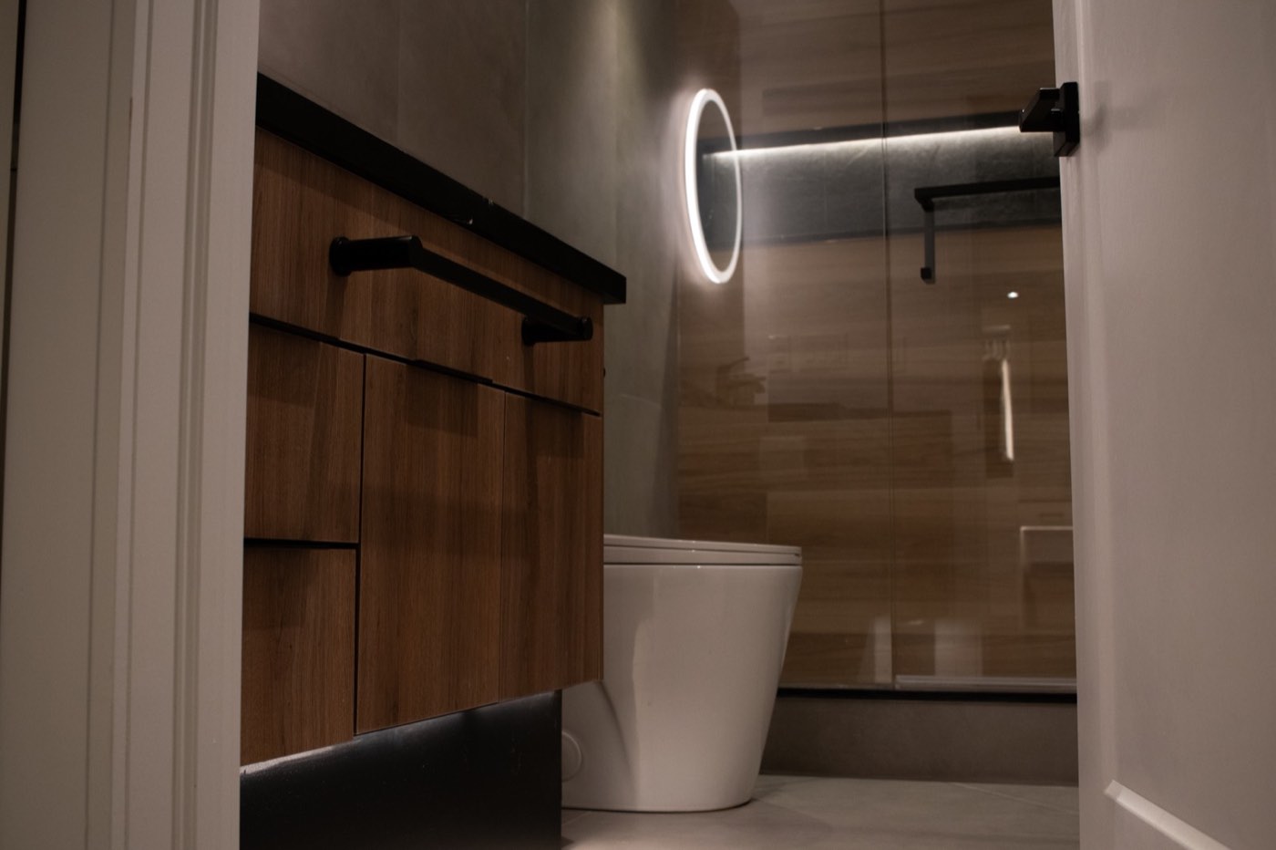 Washroom with walnut vanity and back-lit mirror