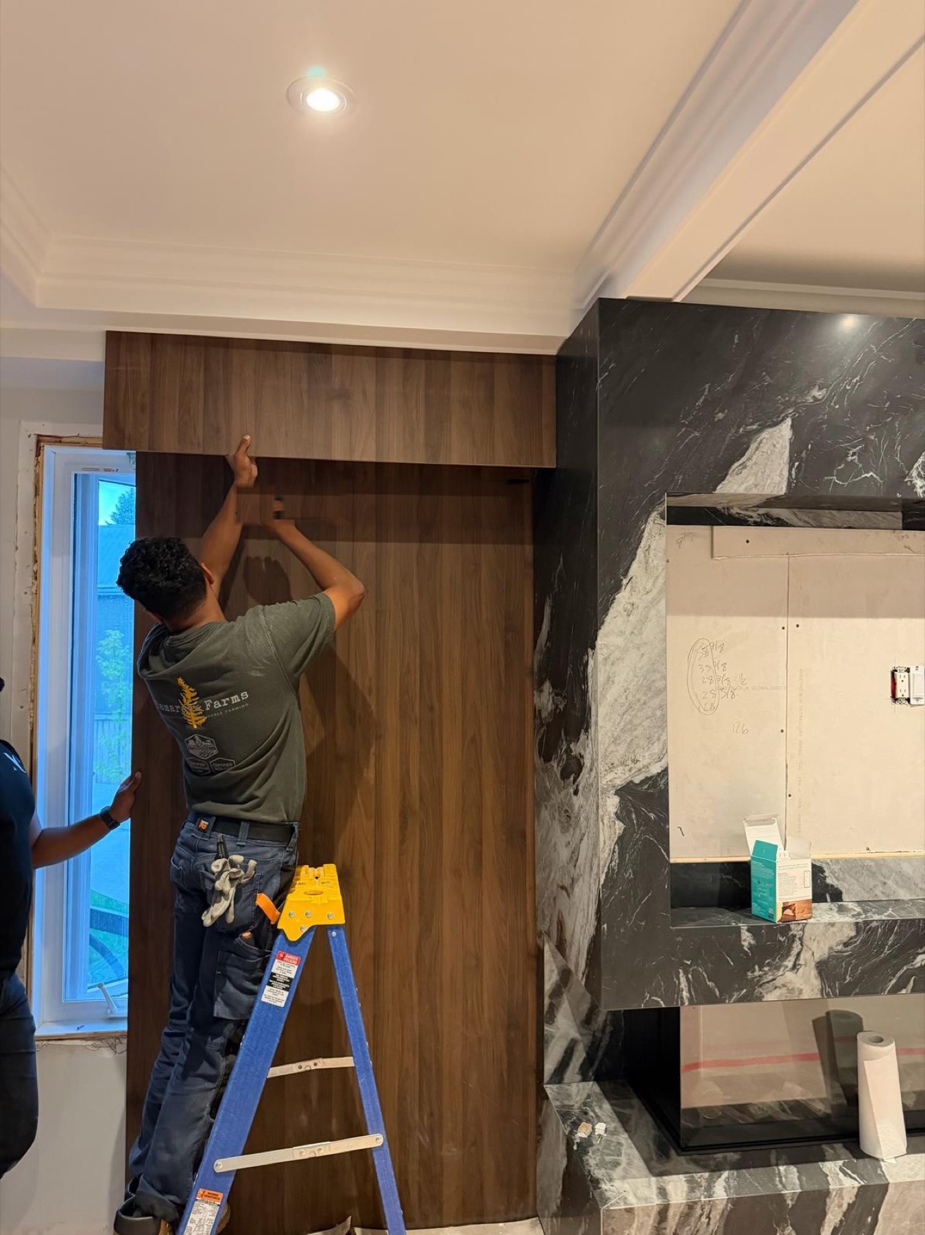 Crew fitting a walnut panel beside a black marble fireplace