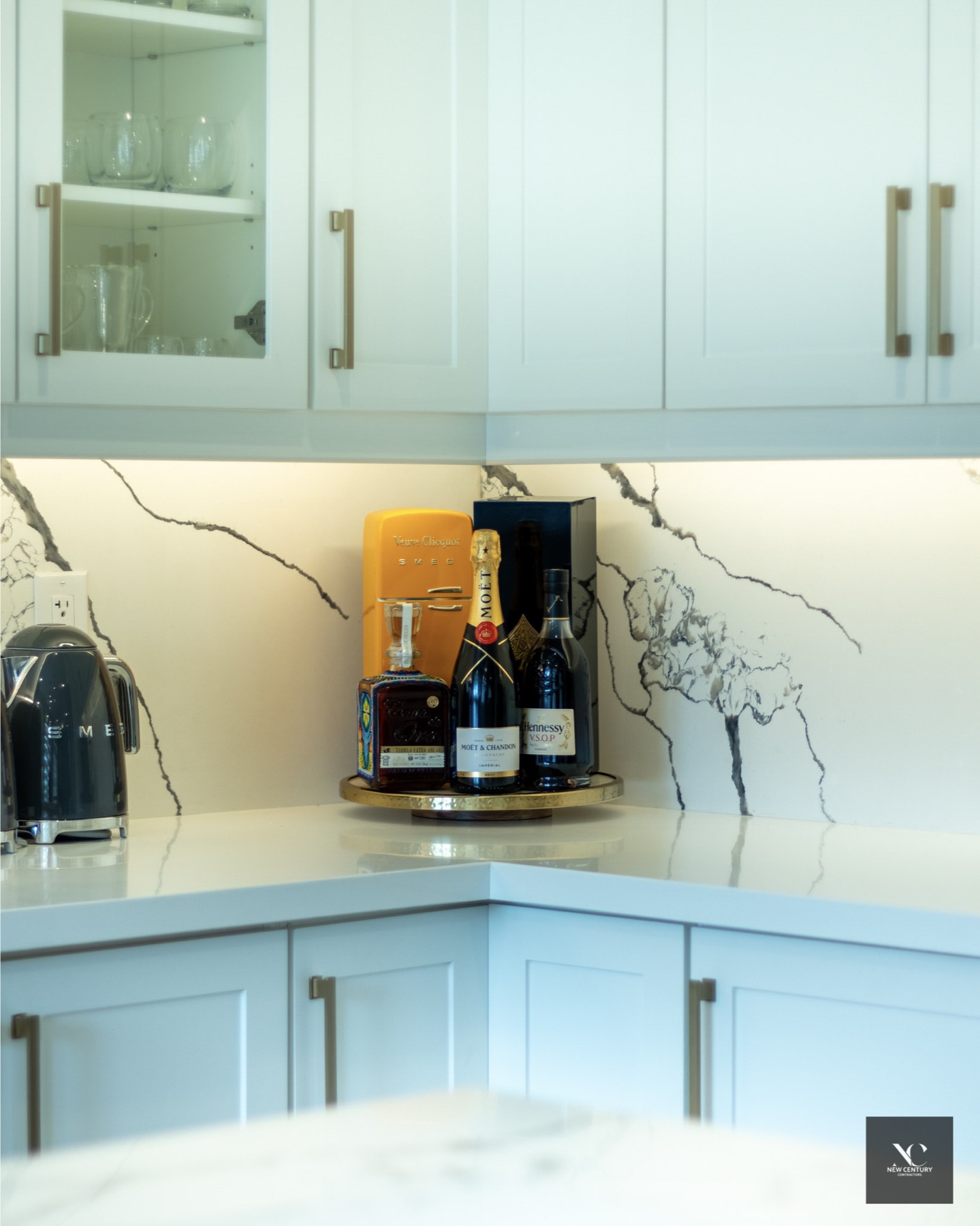 Kitchen corner with marble backsplash, under-cabinet light and a brass bar tray