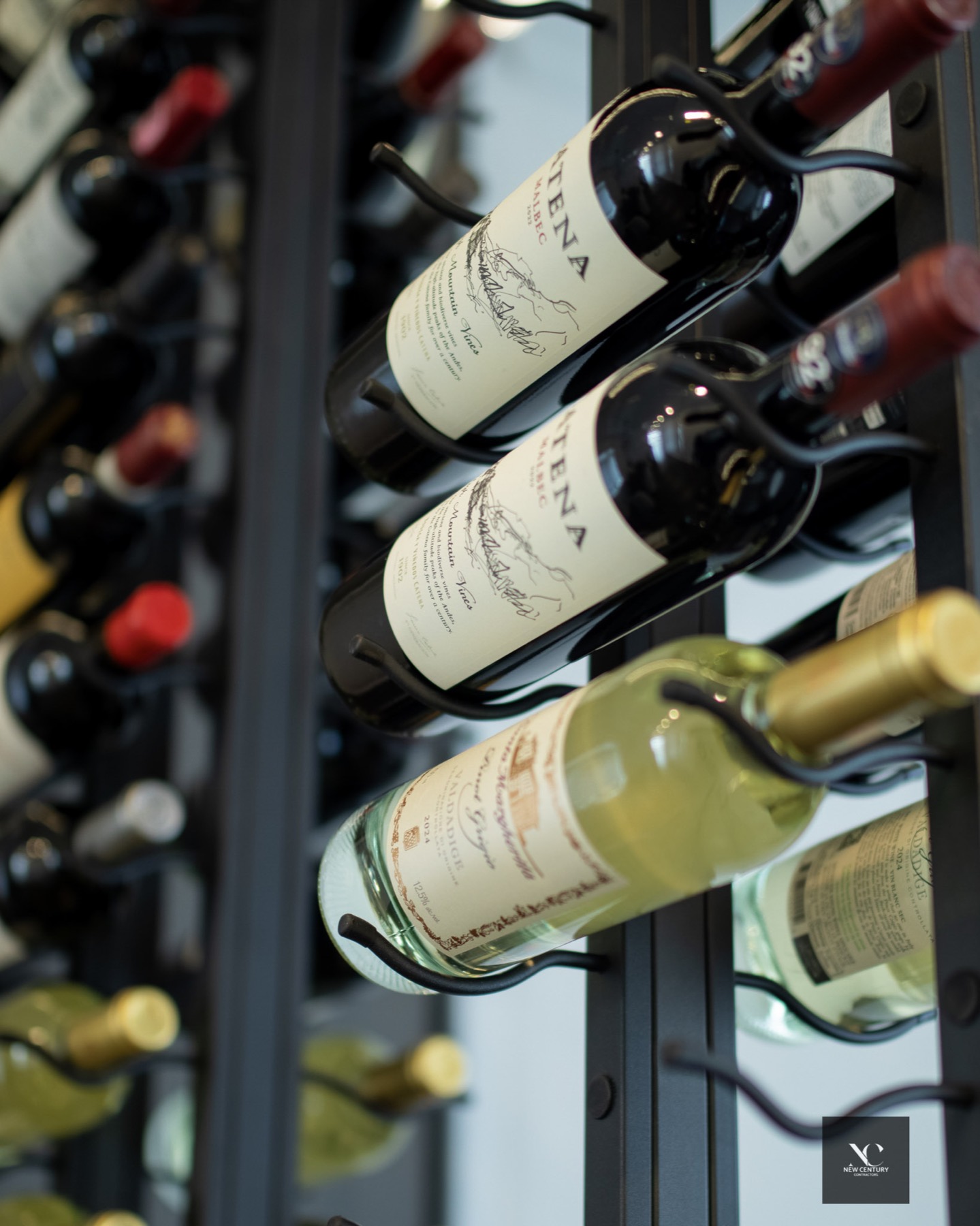 Wine bottles on black steel pegs behind glass