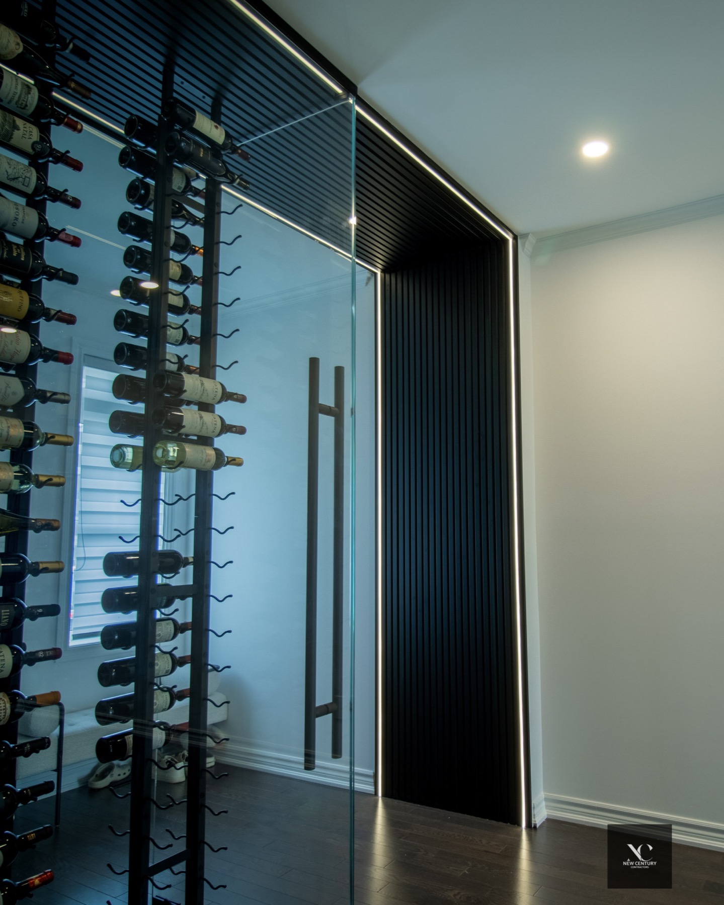 Glass wine room beside a black slat wall with a line of light