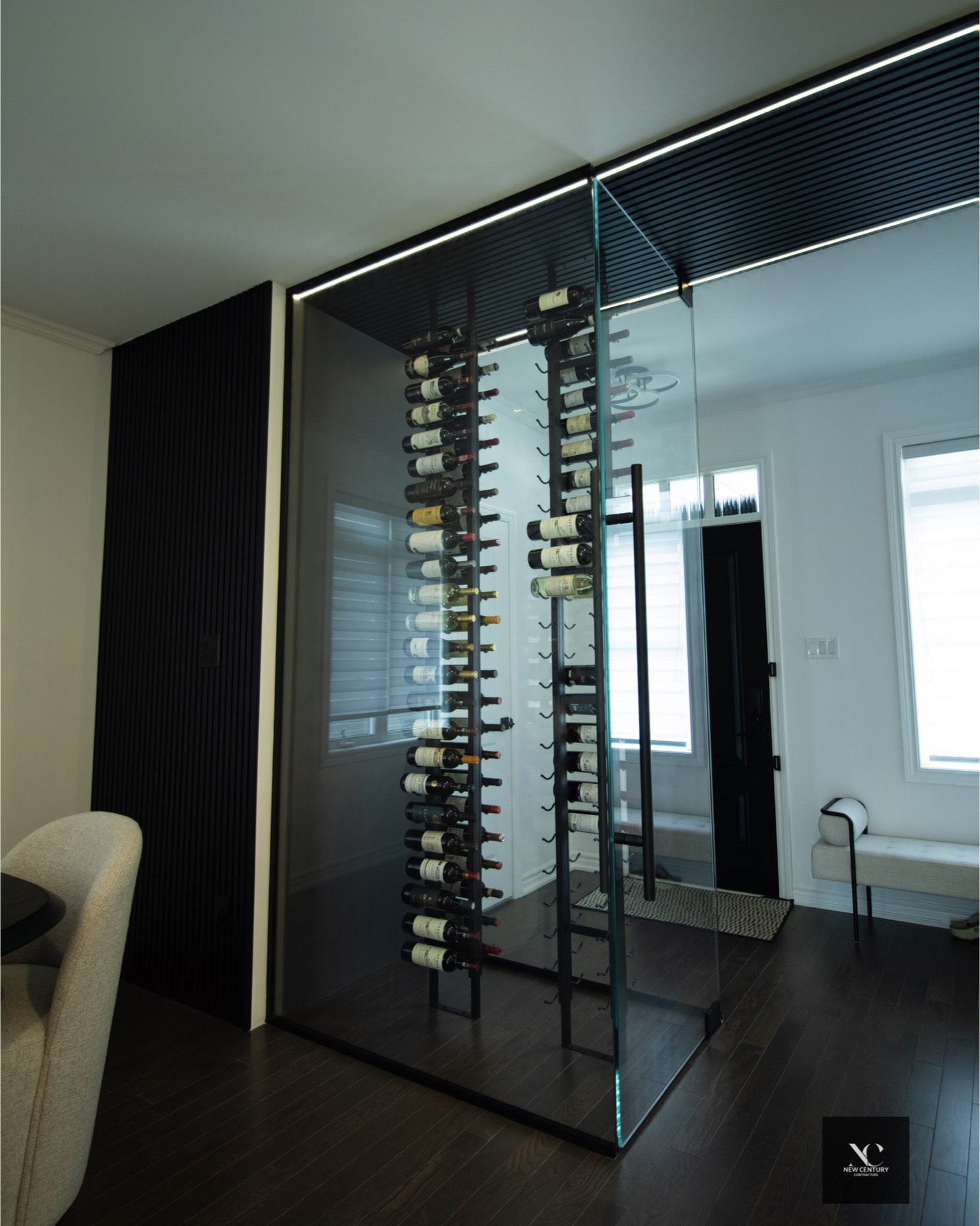 Glass wine room with black steel racking and a slat-panel surround lit by a line of light