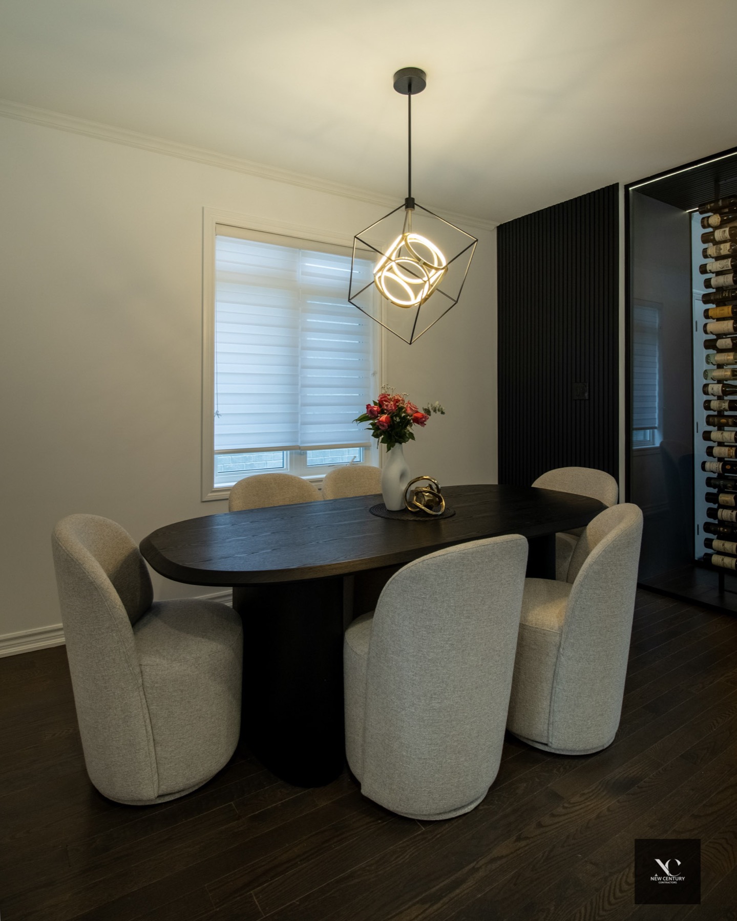 Dining room with oval black table, cube pendant and a glimpse of the wine room