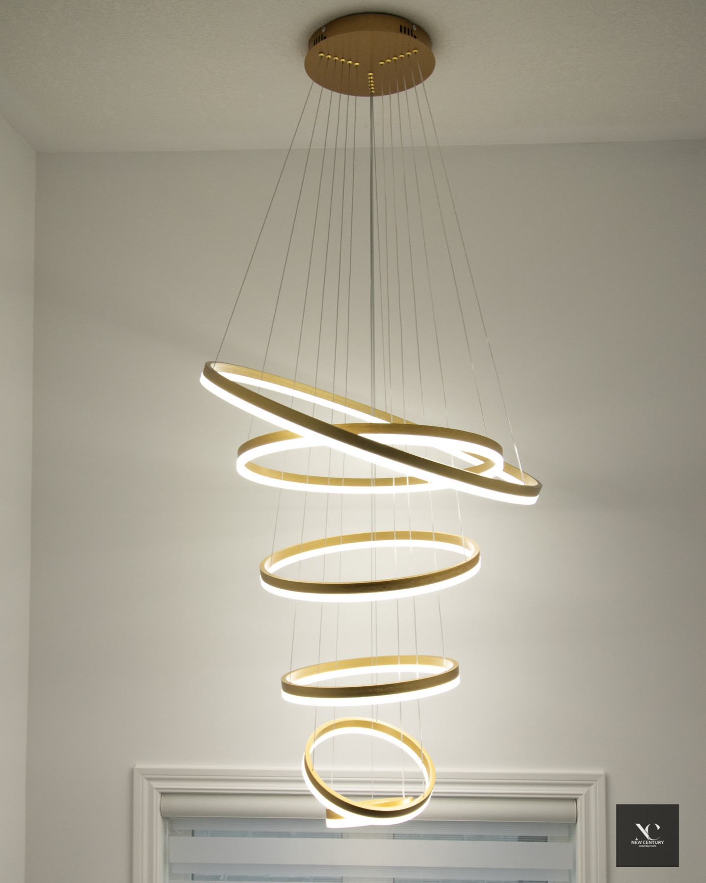 Stacked brass ring chandelier over a stairwell window